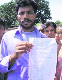 Lalu Naik, a Christian refugee at the Raikia camp, shows the letter in which his family has said it is willing to embrace Hinduism