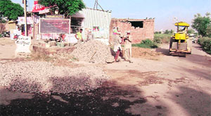 Labourers fill a pothole on the Chhapar road at Mandi Ahmedgarh on Wednesday.