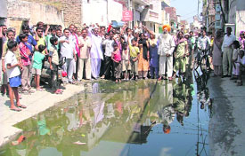 Residents of Ambedkar Nagar stage a protest as sewer overflows; and (right) contaminated water stored in a bottle.