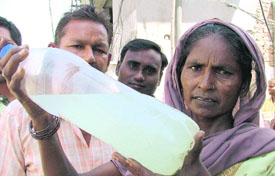 Residents of Ambedkar Nagar stage a protest as sewer overflows; and (right) contaminated water stored in a bottle.