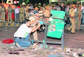 Policemen inspect a dustbin at the site of blast near the Gopaldas Building at Connaught Place in New Delhi