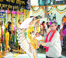 A priest places a child in front of the idol of Baba Sodal for his blessings on the occasion of Sodal Mela in Jalandhar 
