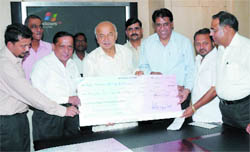 BSES officials hand over a cheque to union minister of power Sushil Kumar Shinde for Bihar flood victims in New Delhi 
