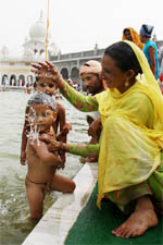 A child gets a holy bath at Guru Ki Dhab in Faridkot 