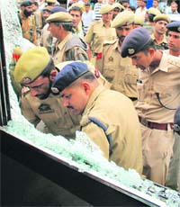 Policemen examine the damage caused to a minibus in a grenade blast at Lal Chowk in Srinagar