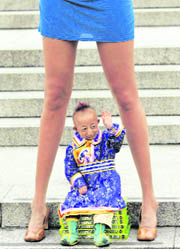 He Pingping from Inner Mongolia, Chinas autonomous region, the worlds smallest man (74.61 cm), sits underneath Svetlana Pankratova from Russia, the Queen of Longest Legs (132 cm), as they pose at Trafalgar Square in London, on Tuesday.
