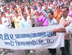 PTA teachers holding a candlelight protest in front of the deputy commissioners office in Mandi on Thursday.