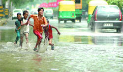 Children play on a waterlogged road in New Delhi