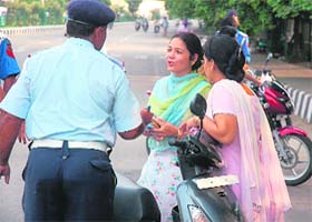 A policeman fines two women drivers for violating traffic norms in Jammu