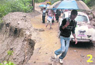 People carefully treading the rain-damaged road.