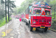 A long row of heavy vehicles stranded due to road damage and landslides.