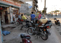 Motor mechanics use the pavement for repair work hampering pedestrians.