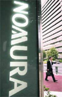 A man walks past a signboard of a Nomura Securities branch in Tokyo on Monday. Japan's Nomura Holdings has reached a deal to buy the Asian operations of Lehman Brothers, a source said on Monday, outbidding other banks seeking to scoop up Lehman's Asia group on the cheap.