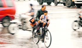 A father-son duo scurries home as rain lashes Jammu