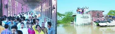 People take to the Iron Yamuna Bridge after the Delhi government closed the Old Yamuna Bridge for rail and road as the river continued to flow above the danger mark on Wednesday. People marooned in flood ask for help in Usmanpur