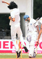 The Rest of India opener Rahul Dravid looks back at the stumps as Delhi pacer Ishant Sharma celebrates his dismissal. 