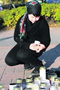 A resident lights a candle in front of the vocational school in Kauhaijoki where a student shot dead 10 persons on Tuesday, about 350 km from Helsinki