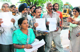 Occupants of Jhota Kut Colony, Sector 71, flash court papers against their eviction in Mohali on Thursday.