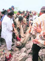Volunteers and paramilitary forces carry the body of a suspected terrorist from his hideout in Karachi on Friday.  Reuters
