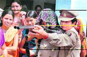 A lady police officer instructs a woman during a weapon training drive at Barara village in Agra district
