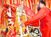 A pujari pays obeisance at Sanatan Dharam temple on the occasion of Durga Puja 