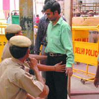 Delhi police personnel frisk a man at the entrance of Jhandewalan Mandir in New Delhi on Tuesday.