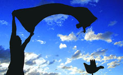 A man silhouetted against the ‘Open Hand’ dries his blanket.