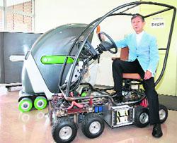 Japan's Keio University professor Hiroshi Shimizu displays a prototype of a personal electric vehicle and its design study model (L) at his laboratory in Kawasaki, suburban of Tokyo, on Saturday. The eight-wheel mobility vehicle is powered by lithium battery and can drive at a maximum speed of 100kmh. 