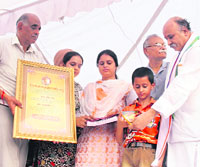 Family members of Kuldeep Kumar, who died during the land row agitation, is honoured by VHP general secretary Praveen Kumar Togadia (extreme right) and Leela Karan Sharma, convener, Amarnath Sangharsh Samiti, in Jammu on Sunday. 