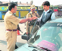 DIG Kashmir Muneer Ahmad checks the identity card of a resident at Budshah Chowk in Srinagar on Sunday. 