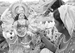 An artist gives final strokes to an idol of Goddess Durga on the eve of Durga Puja in Ambala on Monday.
