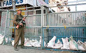 A CRPF man stands guard behind a barricade during the curfew in Srinagar on Monday.