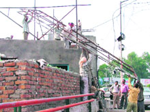 Tehbazari wing of the municipal corporation removes illegal hoardings in Ludhiana on Tuesday.