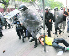 A riot policeman trips over an anti-government demonstrator lying on the ground outside parliament in Bangkok on Tuesday. 