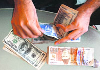 A currency dealer counts Pakistani rupees and US dollars at his shop in Karachi on Wednesday.