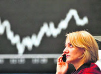 A trader sits in front of a board displaying Germany's share index DAX at the stock exchange in Frankfurt on Thursday. Frankfurt's DAX index of leading shares opened 0.81 per cent higher at 5,054.09 points a day after central banks around the world cut interest rates in a bid to bring calm to financial markets. 