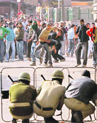 Policemen take cover as protesters hurl stones in Srinagar on Friday. 