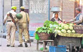 A woman purchases vegetables outside closed shops in Srinagar on Friday. 