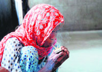Unaware of the new anti-smoking rules, an elderly woman smokes on the premises of the Civil Hospital in Karnal on Saturday.