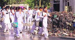 Girls cover their nose as they walk through a filthy road in Jammu. 