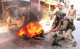 Policemen remove a burning tyre set on fire by youths during a protest in Srinagar on Sunday.