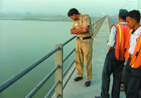 Delhi police jawans and DND security guards look into the Yamuna where a doctor allegedly committed suicide on Monday morning