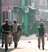Policemen chase away stone-pelting protesters in Srinagar on Monday. 