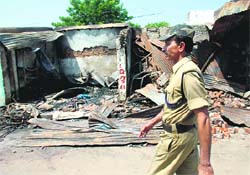 A cop walks past the wreckage of shops burnt during the communal violence in Bhainsa, 300 km from Hyderabad, on Monday. A curfew has been imposed in Bhainsa following the outbreak of violence between Hindu and Muslim communities in the town. 