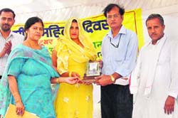 Dr Dilip Gosain presents a trophy to a woman at a function organised by the Krishi Vigyan Kendra, NDRI, on the occasion of World Rural Women's Day in Munak village in Karn