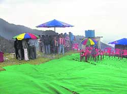 Participants of the Paragliding Pre-World Cup and other officers taking shelter under umbrellas from rain and icy cold winds at Billing on Wednesday.