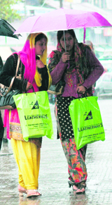 These Kashmiri women walk down a rain-soaked road in Srinagar on Wednesday.