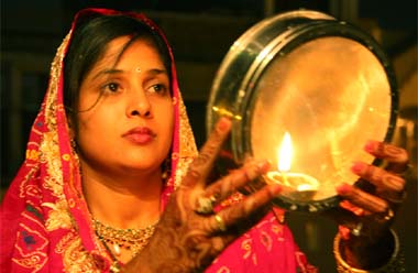 A woman looks at the moon before breaking her fast on the occasion of Karva Chauth in Bathinda