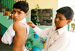 Yashpal, helped by classmate Rajveer, shows his bruises.