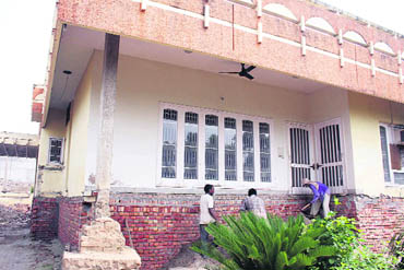 Labourers complete the filling job at a building raised by more than five feet